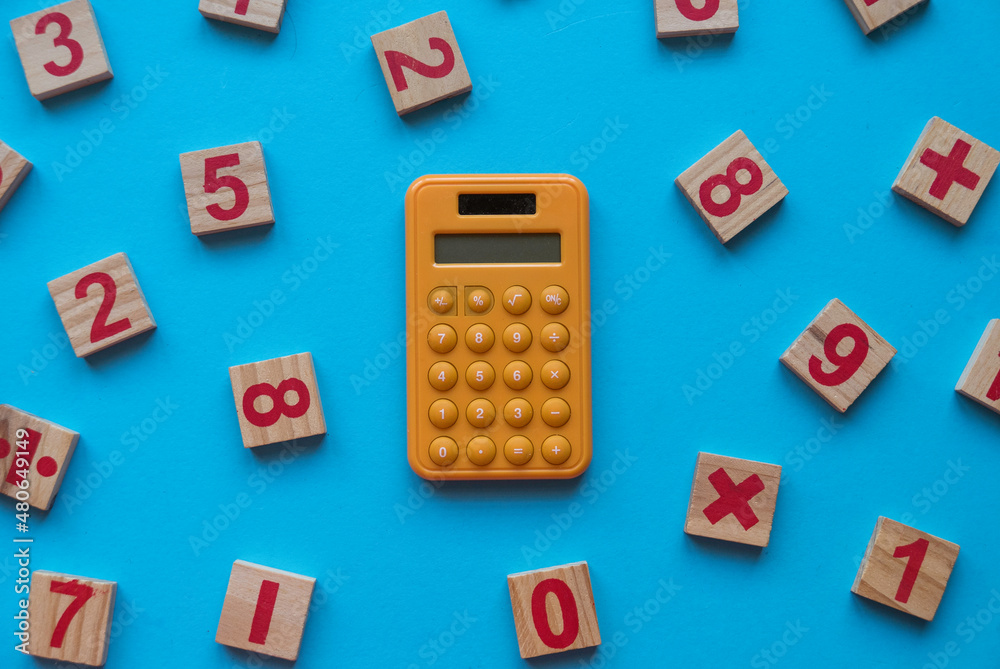 Calculator and a wooden number and mathematical symbol on blue background. Calculator and a wooden number and mathematical symbol on blue background.