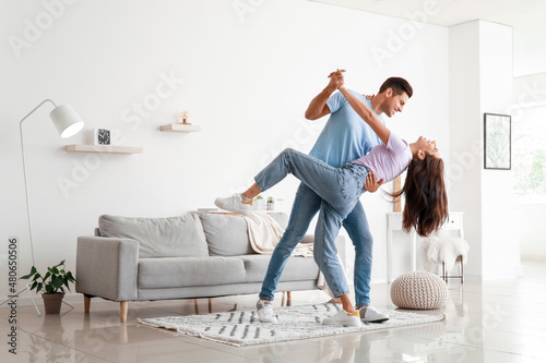 Happy young couple dancing at home photo
