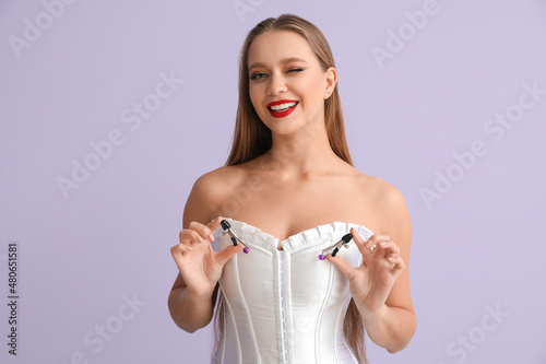 Attractive woman with nipple clamps from sex shop on color background photo
