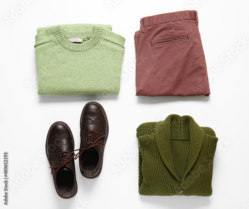 Stylish male sweaters, pants and shoes on white background