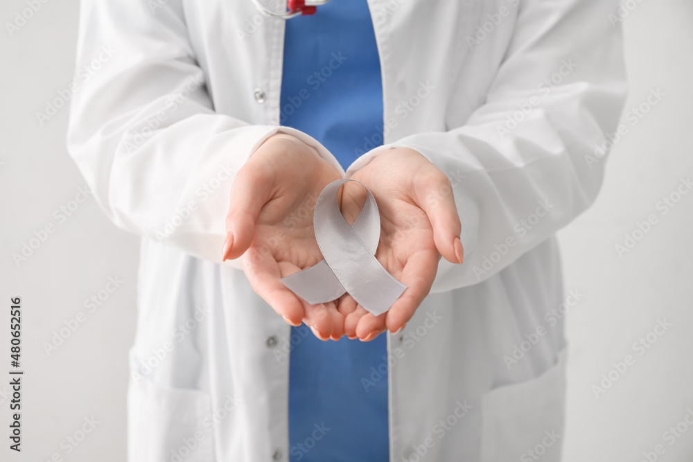Female doctor with Parkinson's awareness ribbon on light background, closeup Female doctor with Parkinson's awareness ribbon on light background, closeup