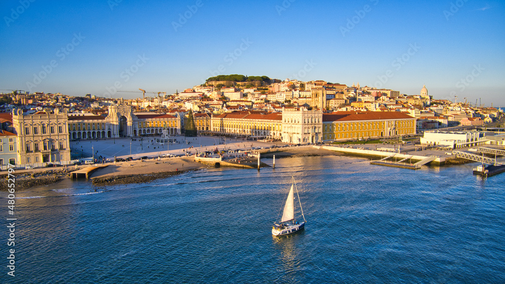 Aerial drone view of Commerce Square in Lisbon, Portugal. Winter sunset. Sailing boat in tagus river.