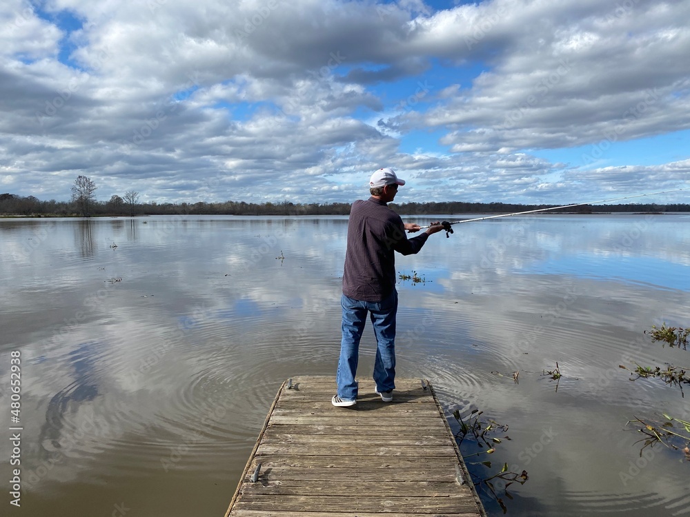 Man fishing on pier at lake