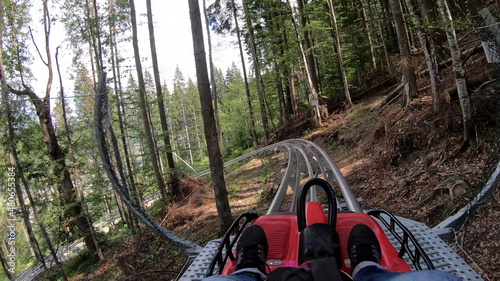 Foto Person rides in fast rodelbahn sledding in mountains in woods among trees