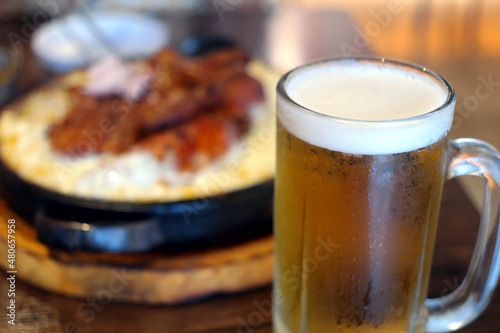 A glass of cold beer and snacks blurred in the background