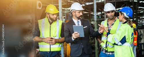 Industrial engineer and businessman in safety helmet working in factory, planning, discussing and training workers with tablet in metalwork place , teamwork and team concept