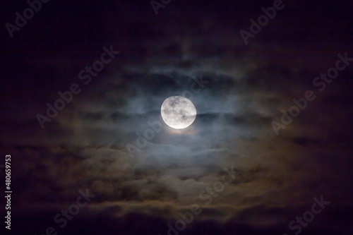 Full moon with colorful clouds in foreground