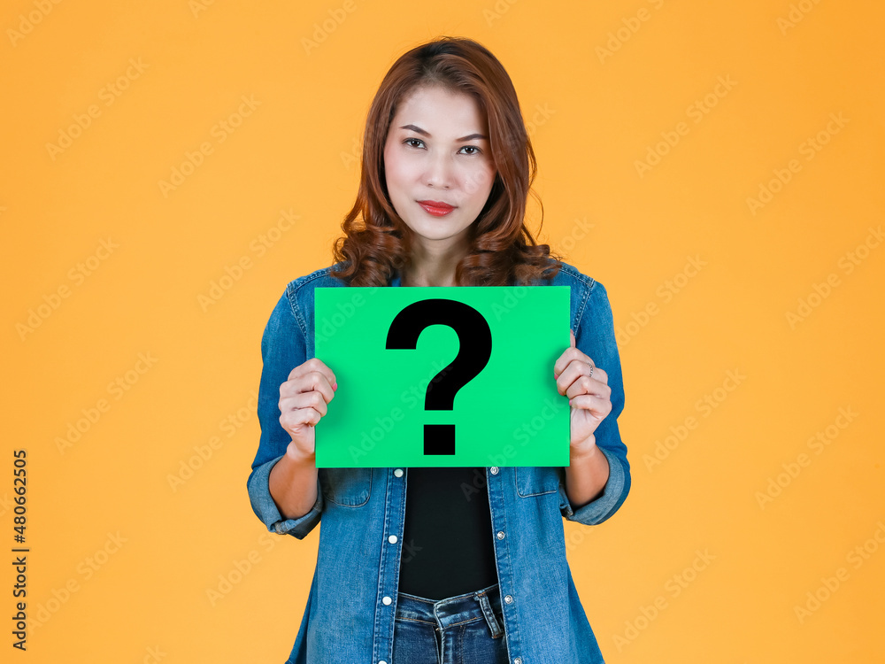 Asian woman in jeans clothes holding a banner with a big question mark on bright color background Asian woman in jeans clothes holding a banner with a big question mark on bright color background