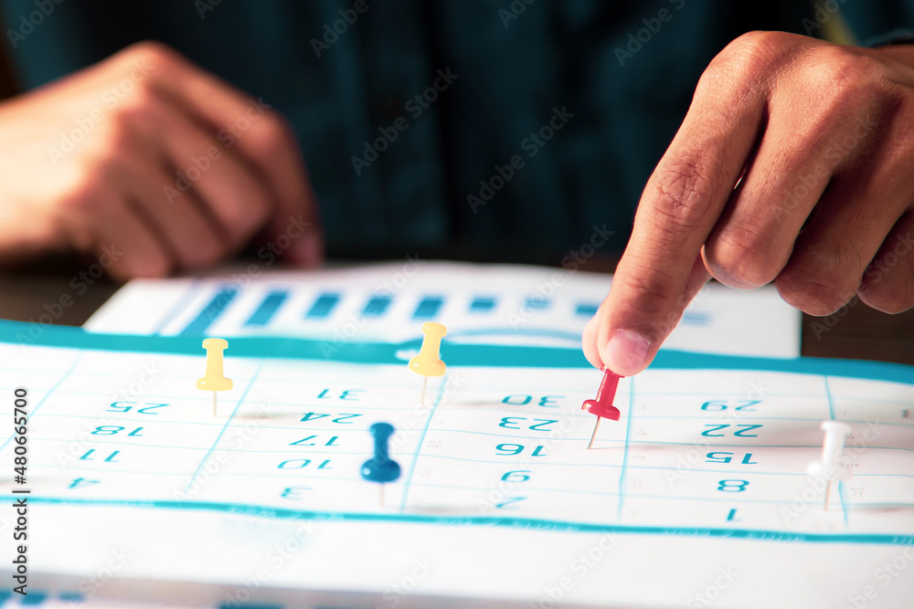 Hand pin on business desk calendar with office equipment concept of event planner or personal organization reminder and schedule or planning. Hand pin on business desk calendar with office equipment concept of event planner or personal organization reminder and schedule or planning.