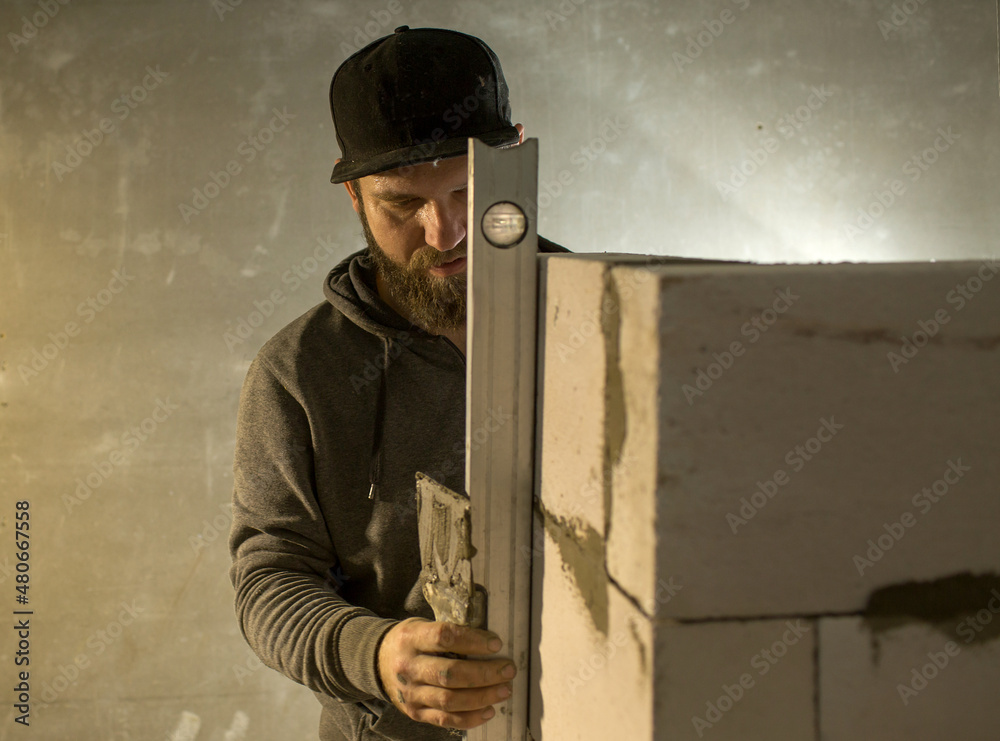 a male builder puts a wall of foam concrete blocks, he spreads a mortar for masonry with a spatula..