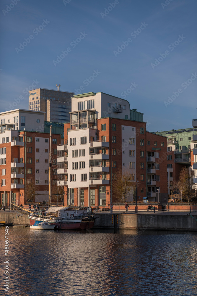 Apartment houses and a pier with sailing boats at the bay Hammarby sjö in the district Södermalm a sunny and snowy winter day in Stockholm
