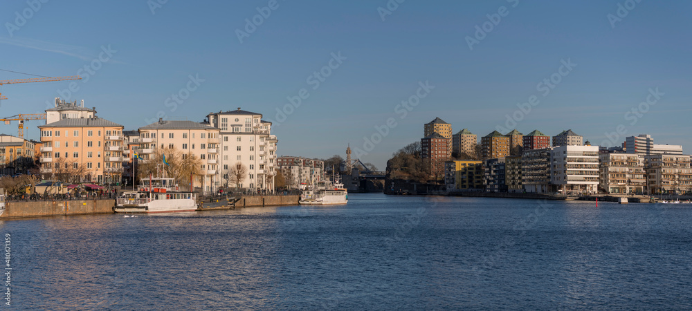 Apartment houses and a piers with boats and ferries at the bay Hammarby sjö in the districts Södermalm, Nacka and Hammarby a sunny and snowy winter day in Stockholm