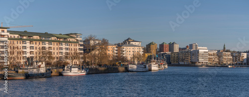 Apartment houses and a piers with boats and ferries at the bay Hammarby sjö in the districts Södermalm, Nacka and Hammarby a sunny and snowy winter day in Stockholm