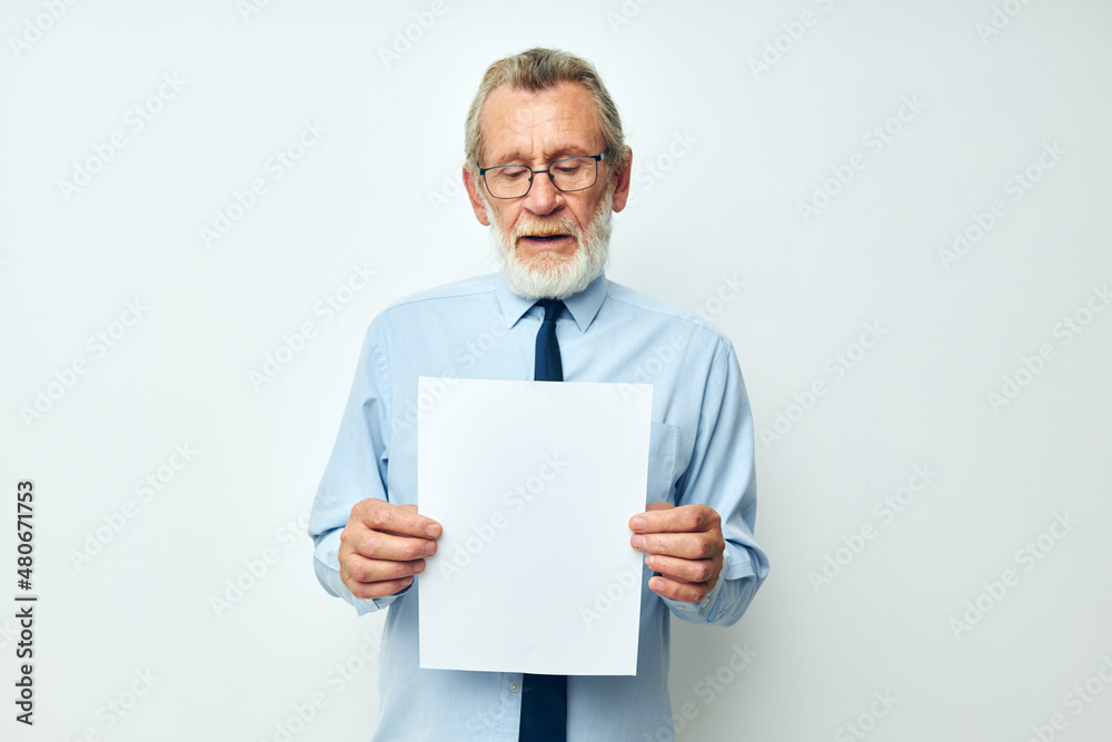 Portrait of happy senior man holding documents with a sheet of paper light background Portrait of happy senior man holding documents with a sheet of paper light background
