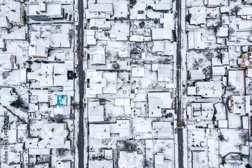 aerial top view of snow-covered rooftops in suburbs residential area