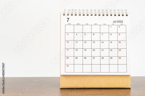 July 2022 desk calendar on wooden table.