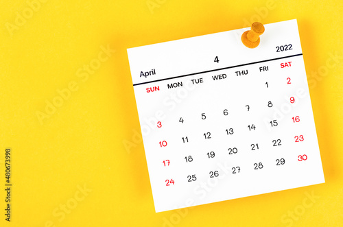 April 2022 and wooden push pin on yellow background.