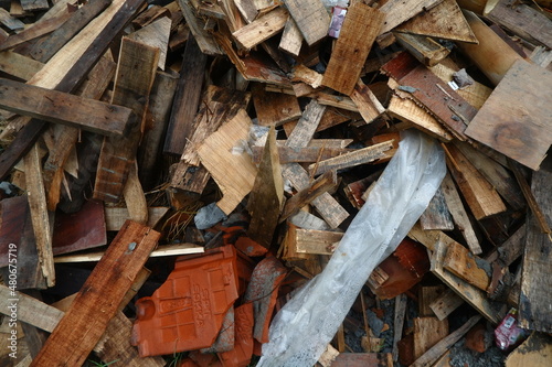 Photo Illustration of Semi-Finished Building and Remaining Building Materials Such as Wood, Bamboo, Barn, Tile Roof, Sand. Everything is placed on the Grasslands