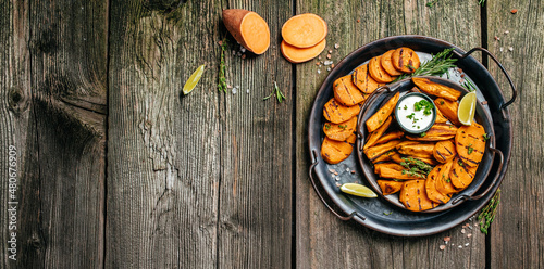 Set of homemade baked sweet potato fries with lime. Sweet potato fries with herbs on wooden background banner, menu, recipe place for text, top view