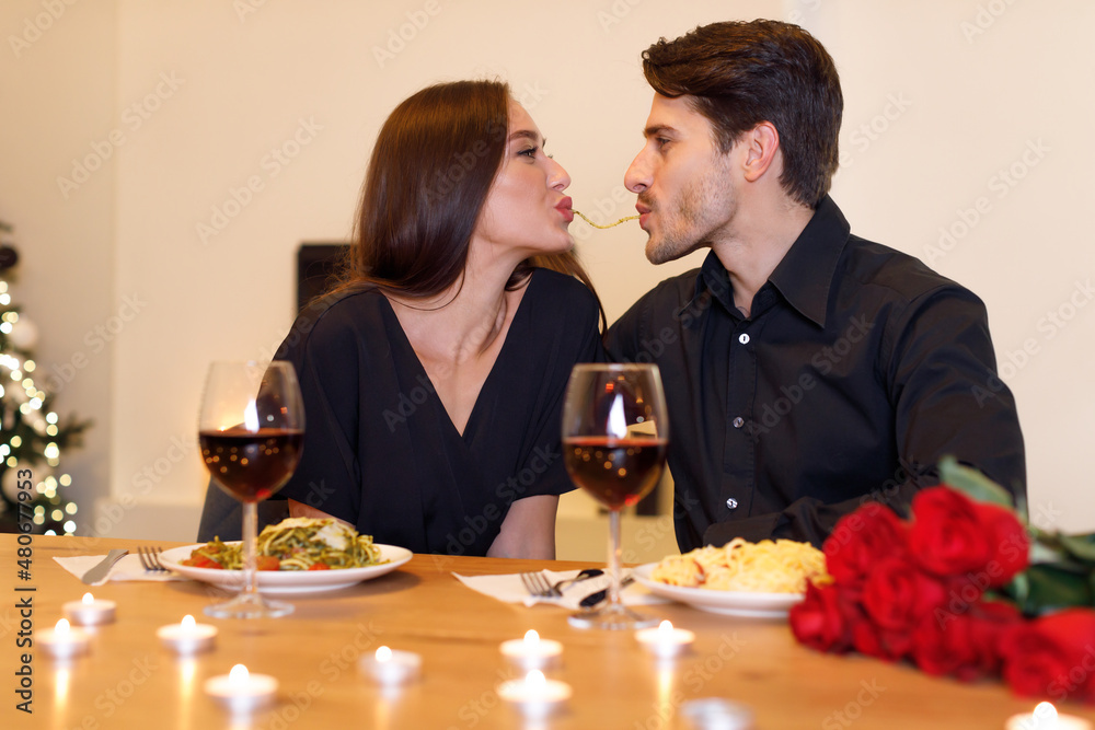 Smiling couple making spaghetti kiss together, celebrating Smiling couple making spaghetti kiss together, celebrating