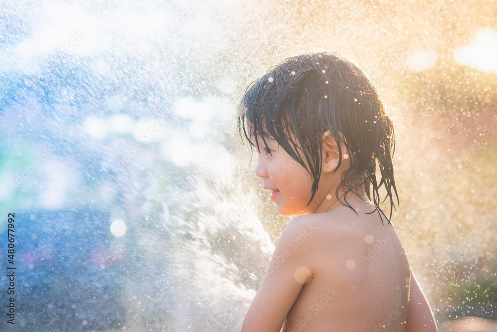 asian boy has fun playing in water from a hose outdoors asian boy has fun playing in water from a hose outdoors