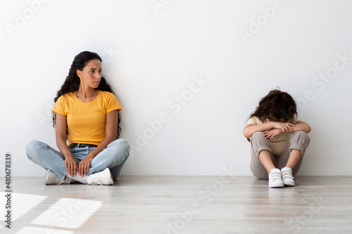 Family Misunderstanding Concept. Worried Young Mother Looking At Her Crying Offened Daughter photo