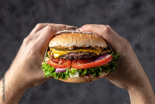 hands holding home made tasty burgers with grilled pork ribs on the wooden table. American food concept. fast food meal. banner, menu, recipe, place for text photo