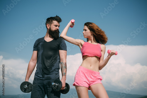 Fit sexy couple on sky background with dumbbells. Fitness concept. Sports couple training with dumbbell. Healthy coupl life style.