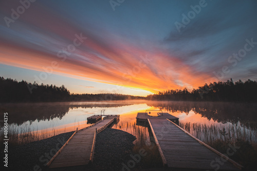 breathtaking sunrise at Lake Jatkonjärvi, which is coloured red, orange, purple, pink and blue by the sun. A mist clings to the surface of the lake, adding to the drama. Hossa national park, Finland photo