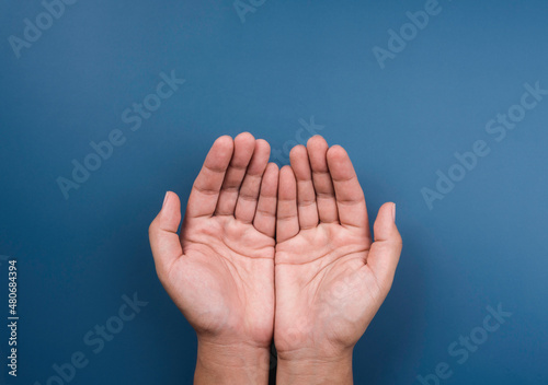 Two empty holding hands gesture isolated on blue background, top view. Giving, requesting, praying, making a wish hand, begging, care concept, outstretched cupped hands.