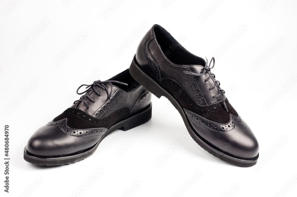 Black imitation leather shoes laced with wide laces. Close-up shot.