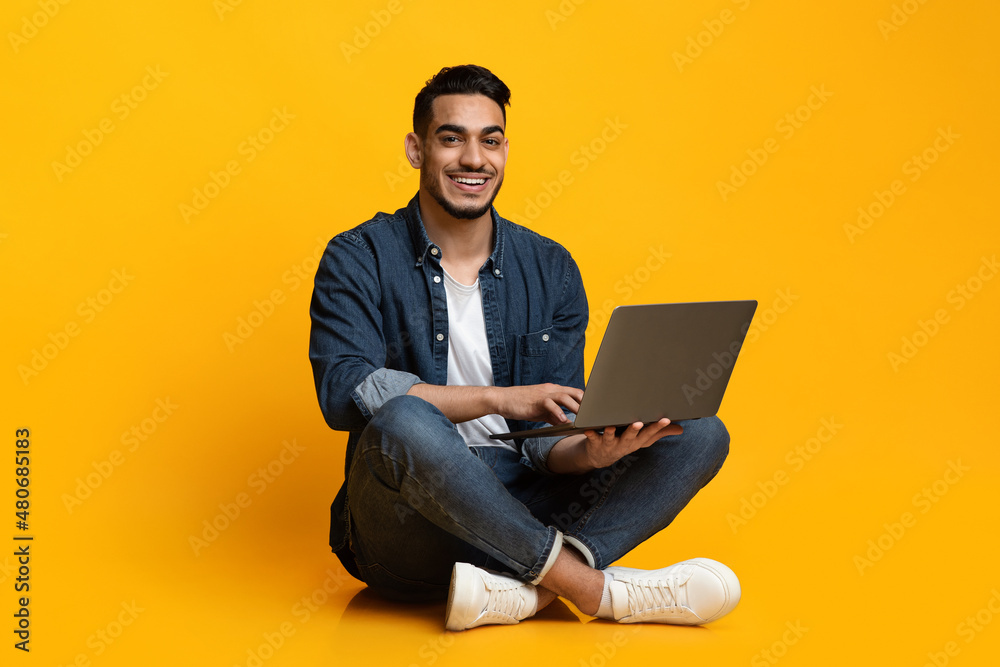 Happy young guy freelancer using modern laptop, programming