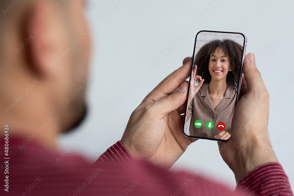 Fototapeta premium Unrecognizable guy using smartphone, having online party with girlfriend