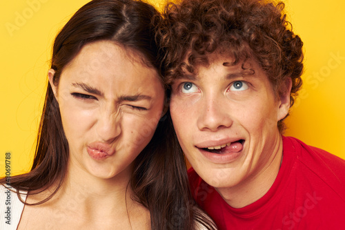 young boy and girl together posing emotions close-up yellow background unaltered
