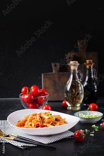 Classic italian pasta penne marinara with mussels and green onions on dark table. Penne pasta with sauce marinara.