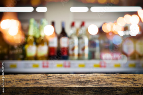 Bartender or male cavist standing near the shelves of wine bottles holds a glass of wine