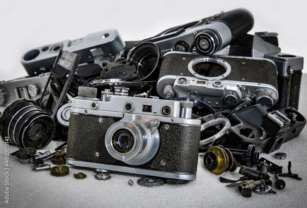 Old film camera on the background of broken and disassembled cameras