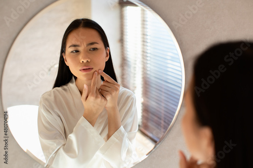 Asian beautiful woman touching her face, pressing pimple photo