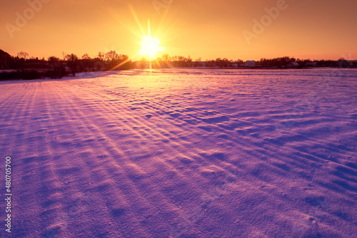 Evening in the countryside. Arable snow-  overed field at sunset