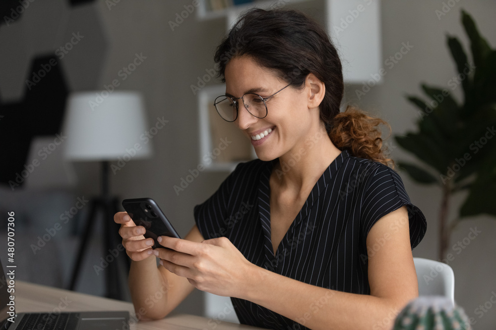 Distracted from computer work sincere happy millennial hispanic caucasian businesswoman in eyewear playing mobile game, communicating distantly in social network, web surfing information online. Distracted from computer work sincere happy millennial hispanic caucasian businesswoman in eyewear playing mobile game, communicating distantly in social network, web surfing information online.