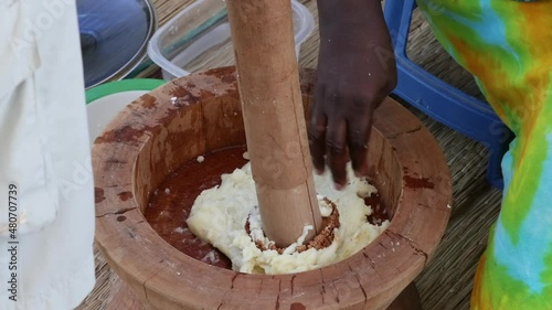 Making pounding fufu dough wooden bowl Accra Ghana. Traditional cooking and food preparation in west Africa. Various different foods prepared by pounding with heavy sticks dough in bowl. photo