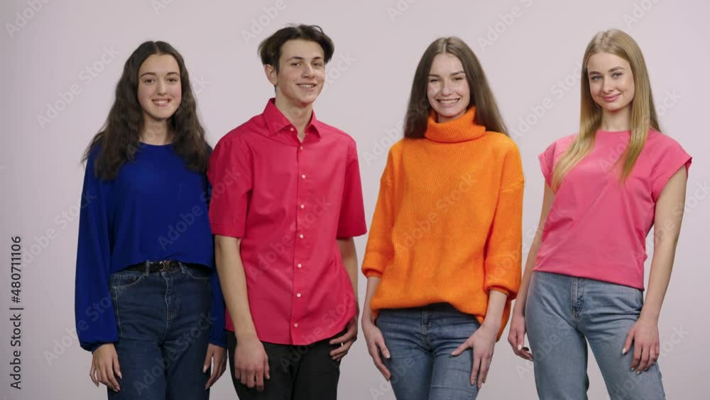 A group of young people looking at the camera, smiling joyfully and ...