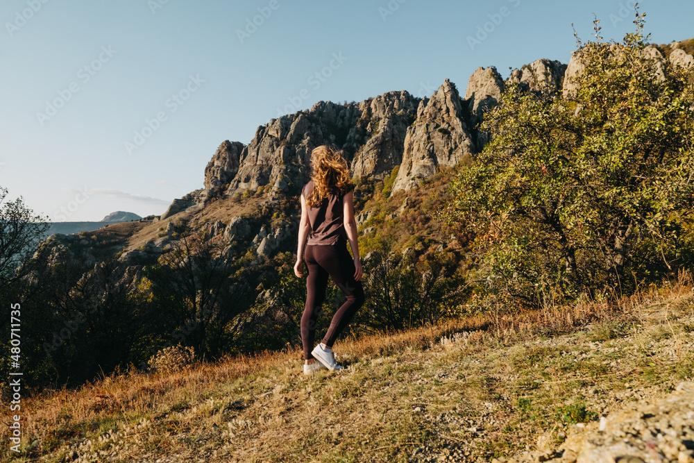 Valley of Spirits Crimea. A girl with long hair stands with her back and looks at the rocks. Against the background of yellow grass and shrubs. Summer