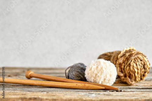 Balls of wool yarn and wooden knitting needles on the table. Hobby craft background with space for text. Concept of knitting, needlework.