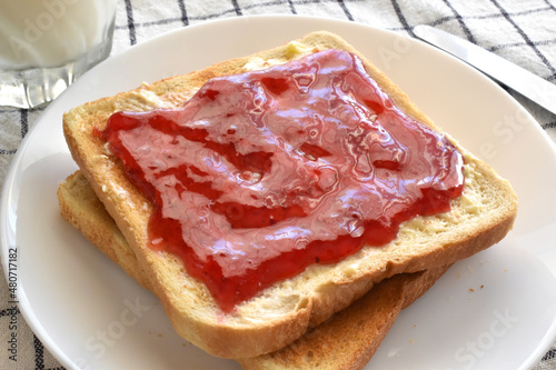 Toast with raspberry jam and butter on a plate. Lovely breakfast at home.
