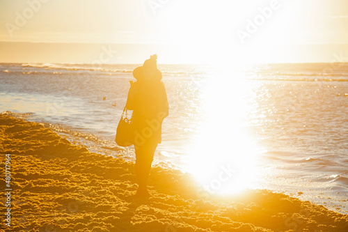Silhouette of a young woman at the beach enjoying sunset