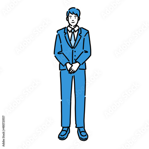 手を組んで立っているスーツの男性