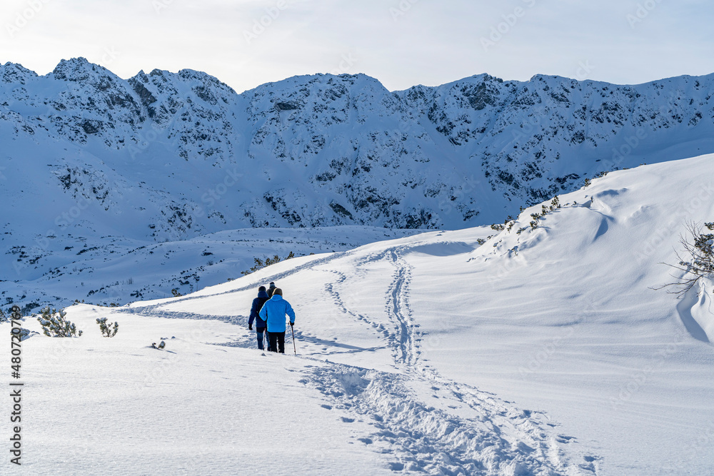 Tatra Mountains, Winter mountain landscape in the Tatras, tourists climb the snowy slopes, views of the snow-capped mountains in frosty sunny weather Poland