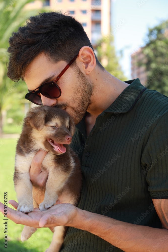 Handsome dark-haired man with his puppy dog, both of them very happy