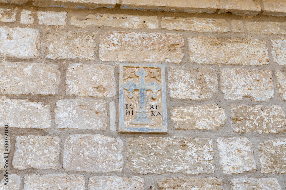 The bas-relief  depicting a cross on  wall above the entrance to  St. John the Baptist Monastery of the Franciscan Order near Israeli side of of Qasr El Yahud, in the Palestinian Authority, in Israel